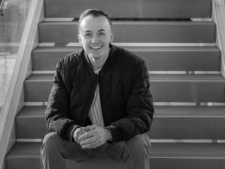 Van Taylor seated on concrete stairs in a black-and-white portrait.